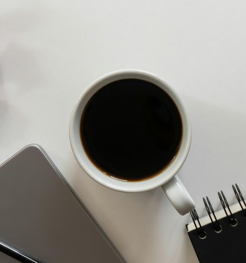 Coffee cup, notebook and laptop on a desk